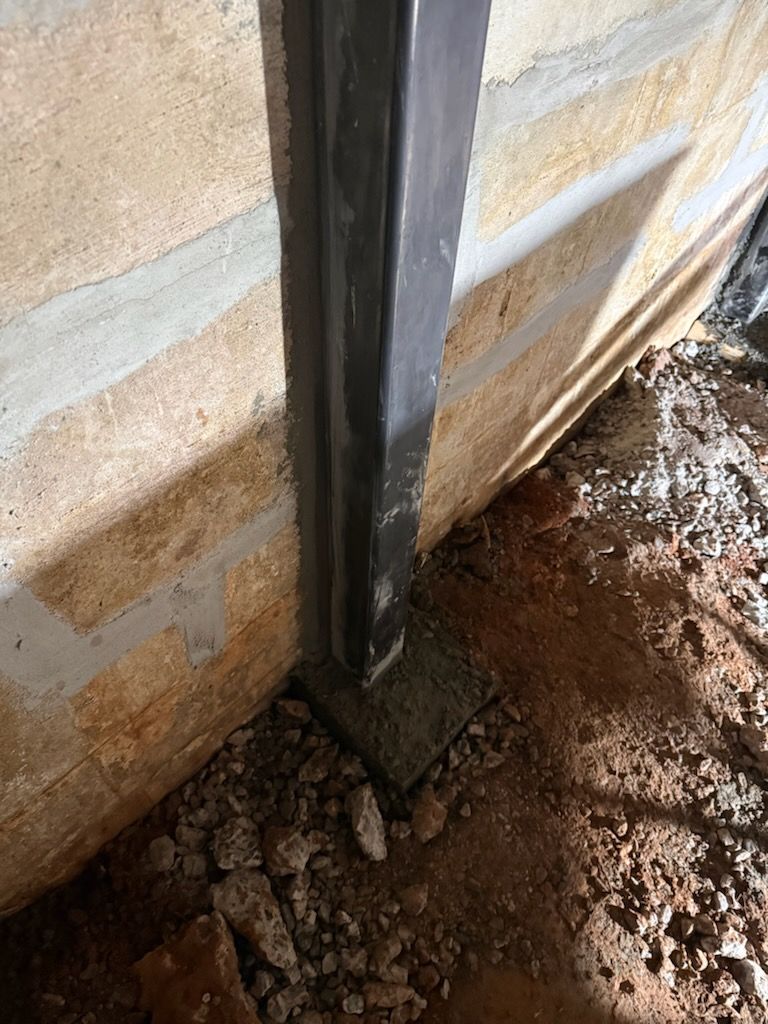 Steel wall beam set at the base of a block basement wall