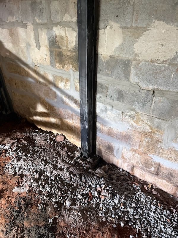 Steel wall beam installed along a block wall with drain pipe and stone