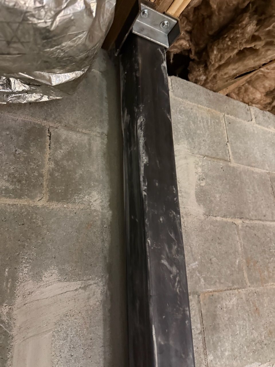 Steel wall beam fastened to the floor framing above a block wall