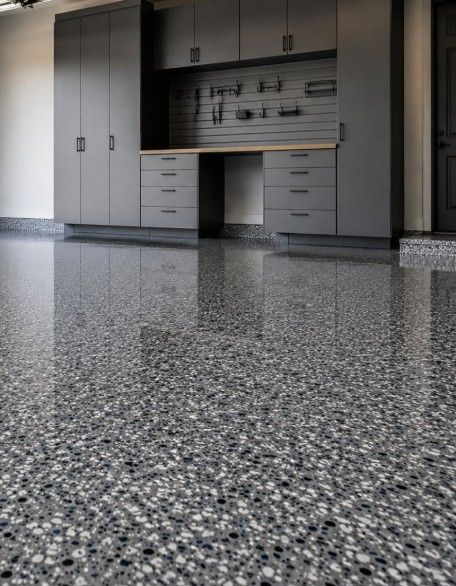 Gray metal storage cabinets and a workbench with a pegboard wall above a glossy flake epoxy floor