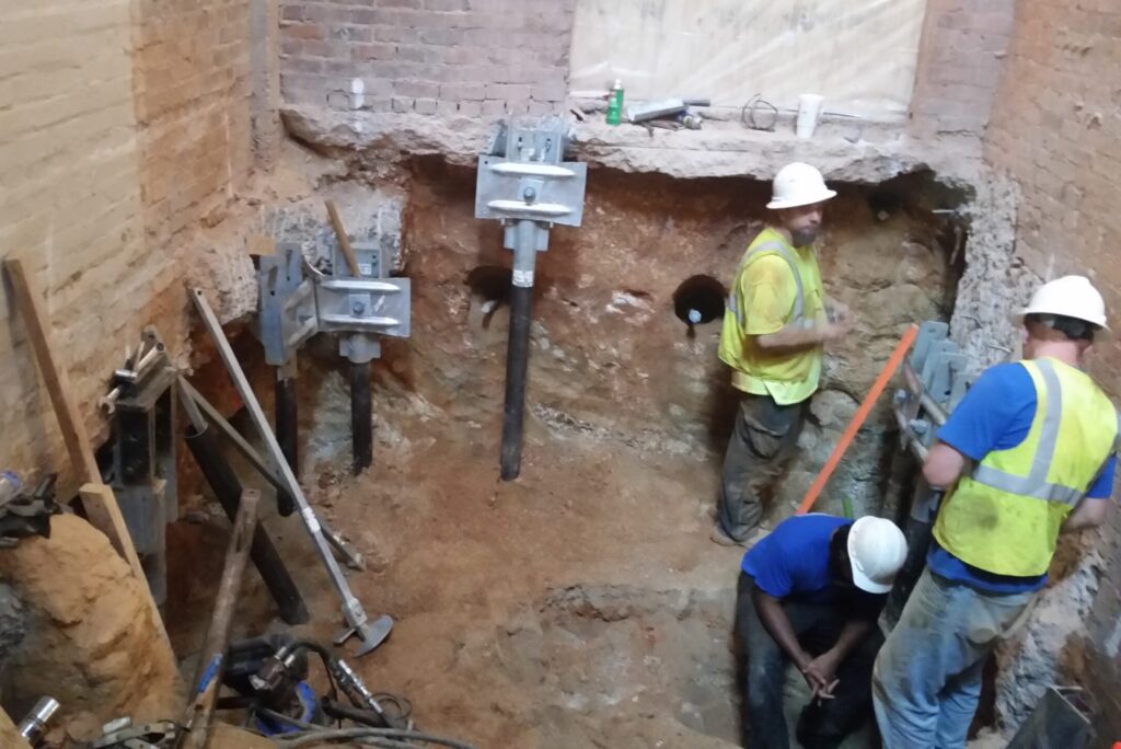 Commercial underpinning crew installing foundation brackets